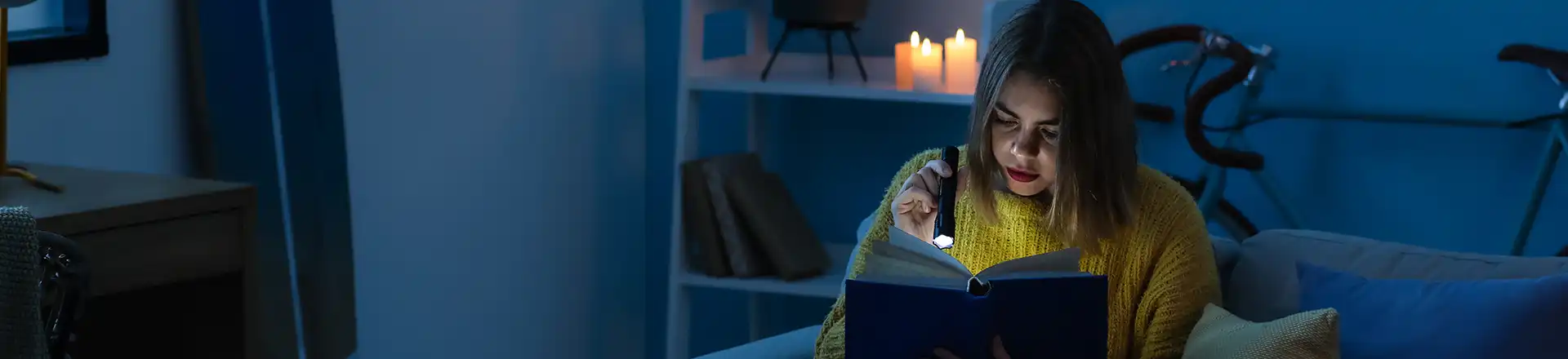 Girl reading book using torch