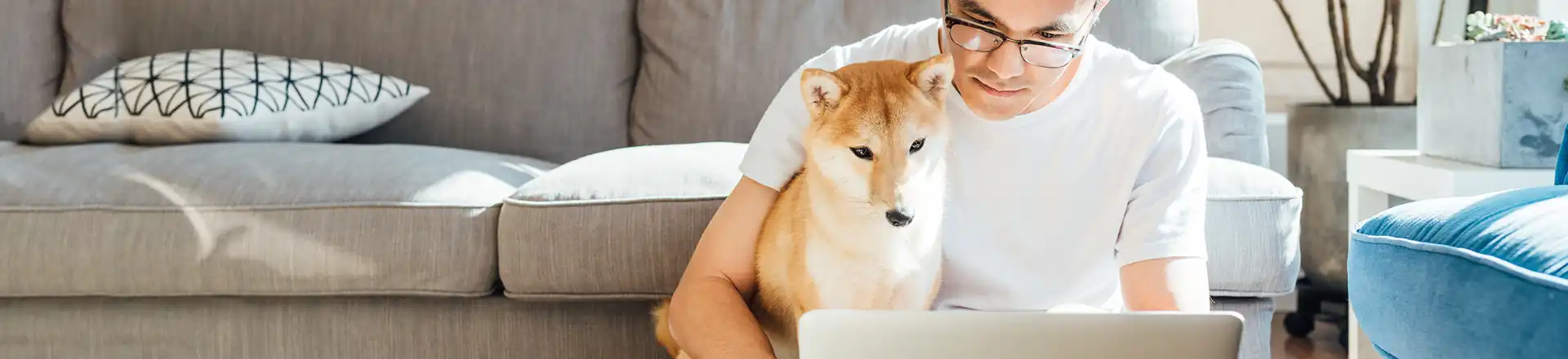 A man working from home on a laptop with a dog